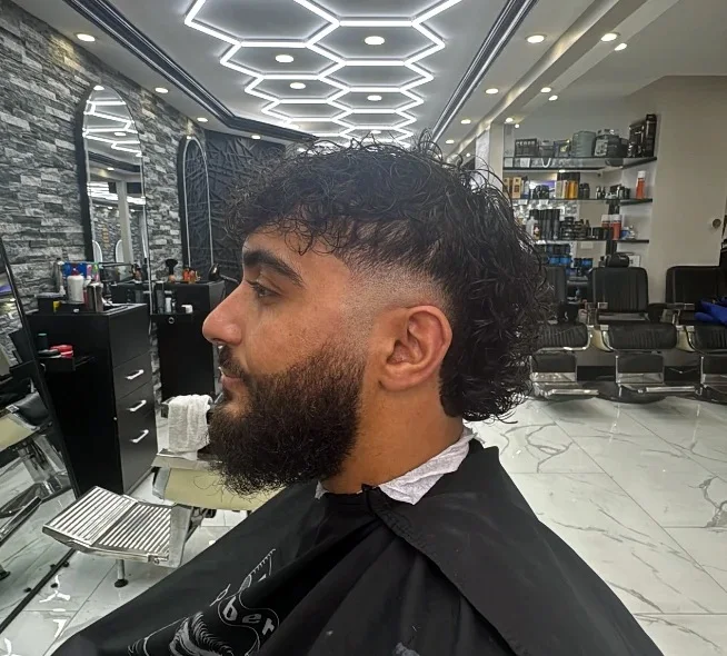 Loose curls with a beard, seated in the shop.